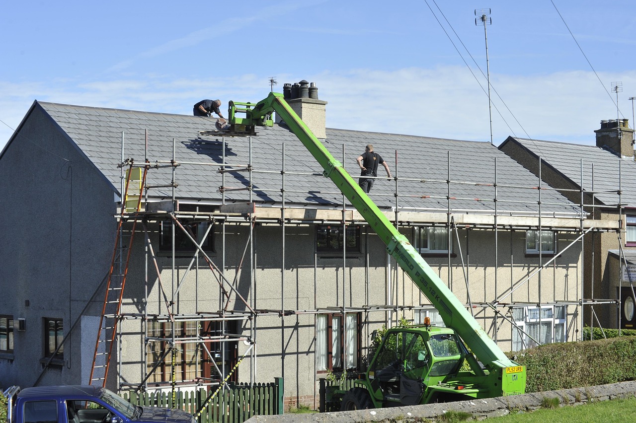 Roofers on scaffolding fitting a new slate roof to a semi-detached house